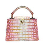 Pink and white crocodile-patterned handbag with gold accents on a light gray background