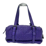 Purple woven handbag with a handle on a white background