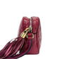 Maroon handbag with gold zipper and tassel on a white background